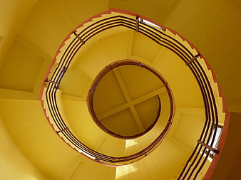 Spiral staircase looking up with yellow walls and red railings