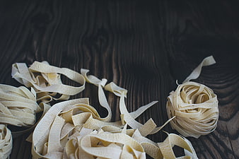 Fresh handmade tagliatelle pasta nests on dark rustic wood