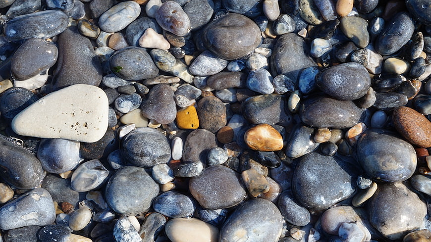 Wet smooth pebbles and stones on a beach background