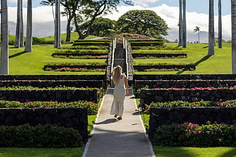 Woman Walking Up Path in Tropical Garden with Palm Trees