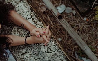 Close-up of woman's hands clasped on stone ledge outdoors