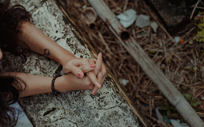 Close-up of woman's hands clasped on stone ledge outdoors