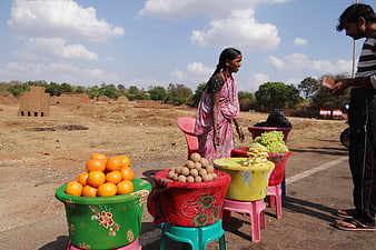 Indian woman selling fresh fruit from decorated baskets on a roadside
