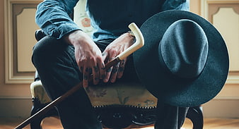 Man with tattoos holding cane and black hat