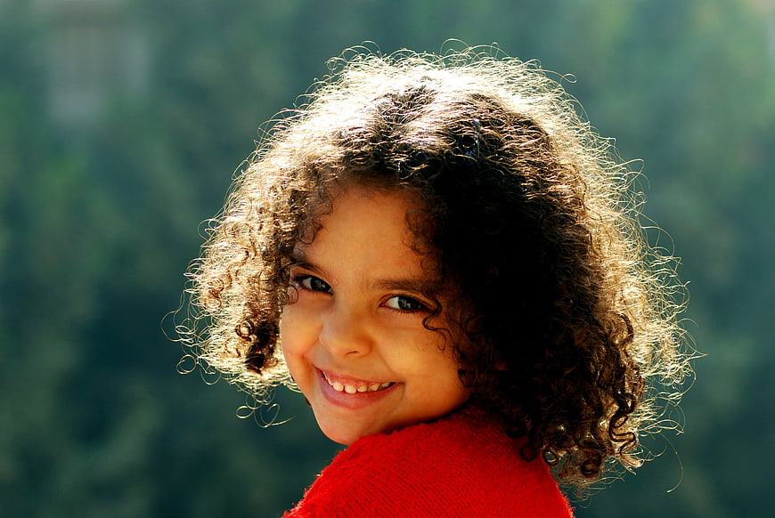 Smiling child with curly hair in red sweater