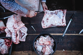Butcher cutting raw pork meat on wooden table top view