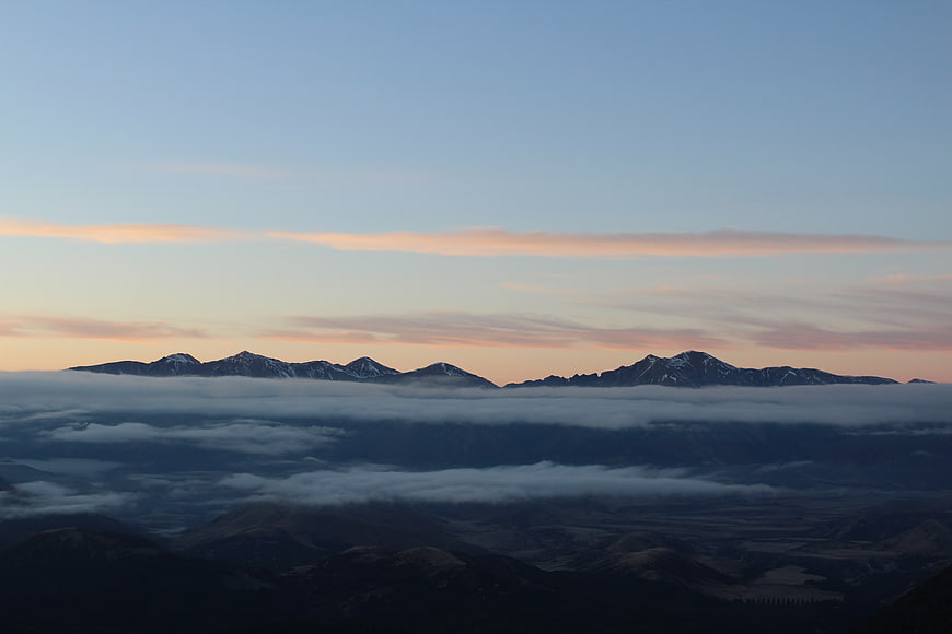 Snow-capped mountain peaks rising above a sea of clouds at sunrise