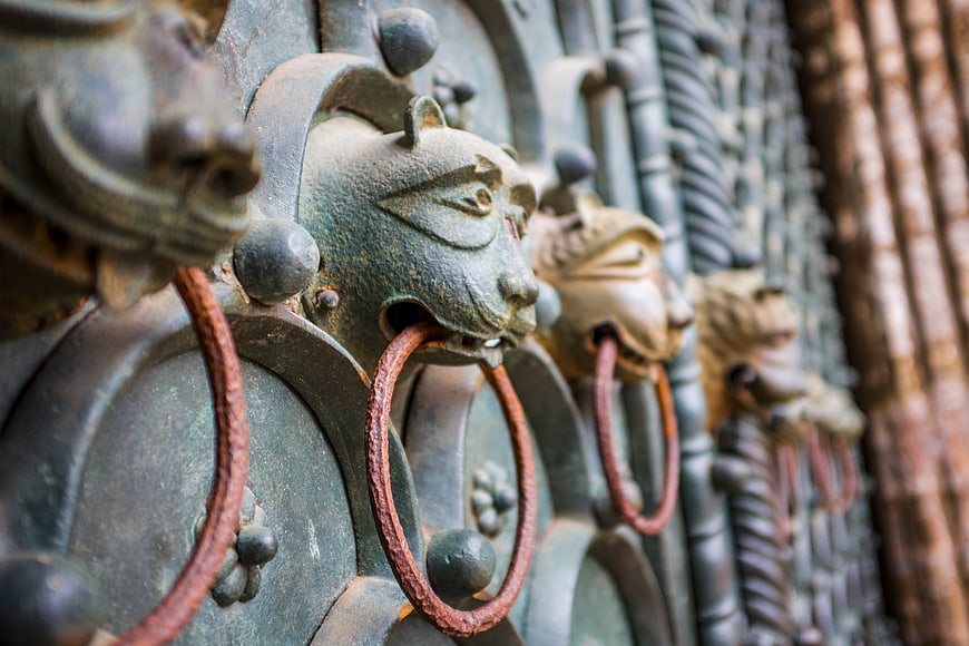 Close-up of ornate metal lion door knockers on a historic door