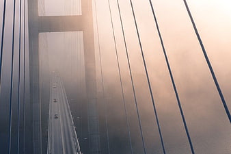 Foggy Suspension Bridge with Cars Driving at Dawn