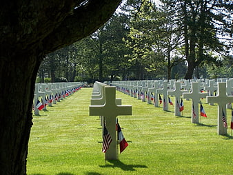 Rows of white crosses in a military cemetery with flags