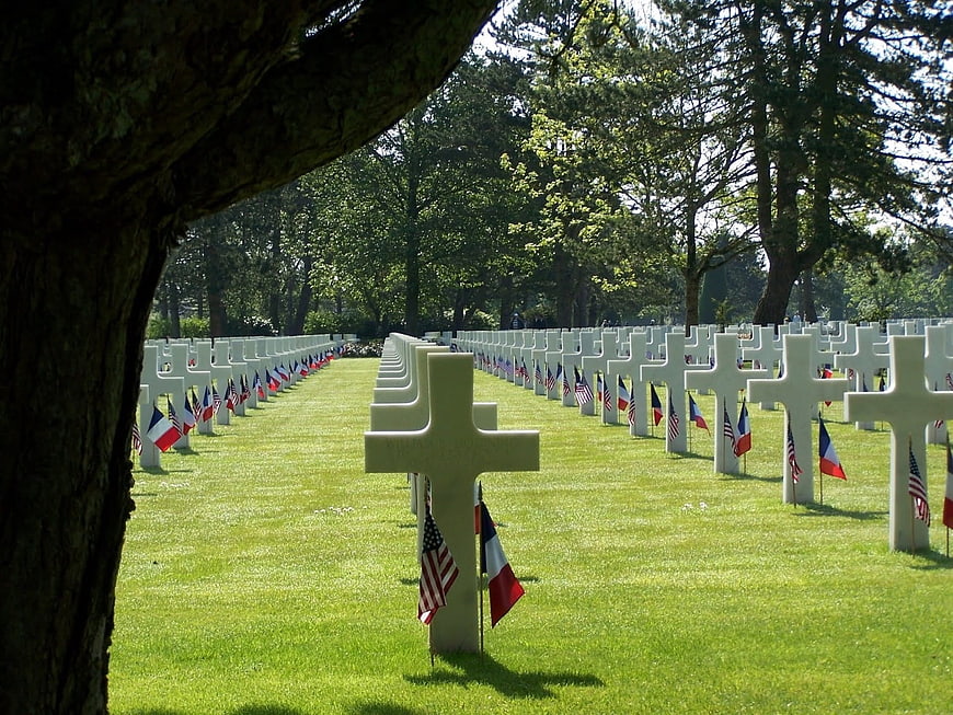Rows of white crosses in a military cemetery with flags