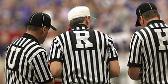 Three Baseball Umpires in Striped Uniforms Conferencing