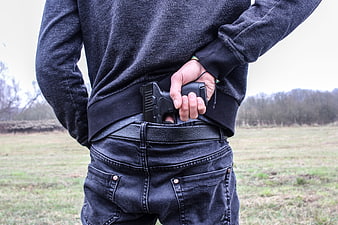Man holding pistol in waistband outdoors