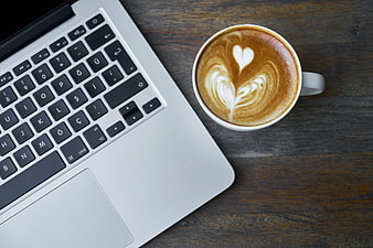 Flat lay of laptop and latte art coffee on wooden desk