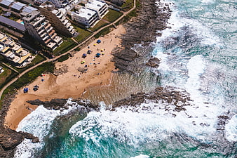 Aerial View of Rocky Beach with Turquoise Waves and Coastal Buildings