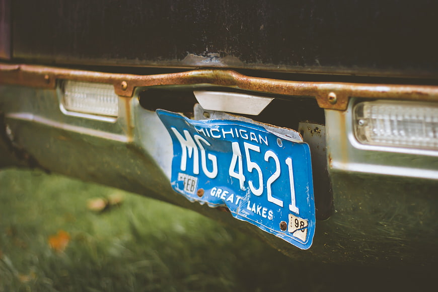 Rusty vintage car bumper with Michigan license plate
