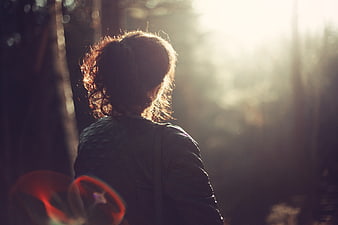 Woman in forest backlit by golden sunlight