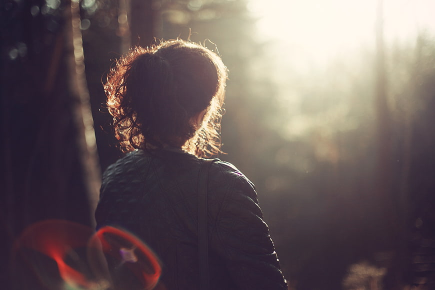 Woman in forest backlit by golden sunlight