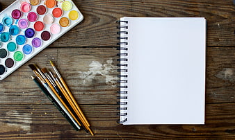 Blank Sketchbook, Watercolor Palette, and Brushes on Rustic Wooden Table