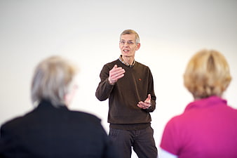 Senior man presenting to two women in a bright indoor setting