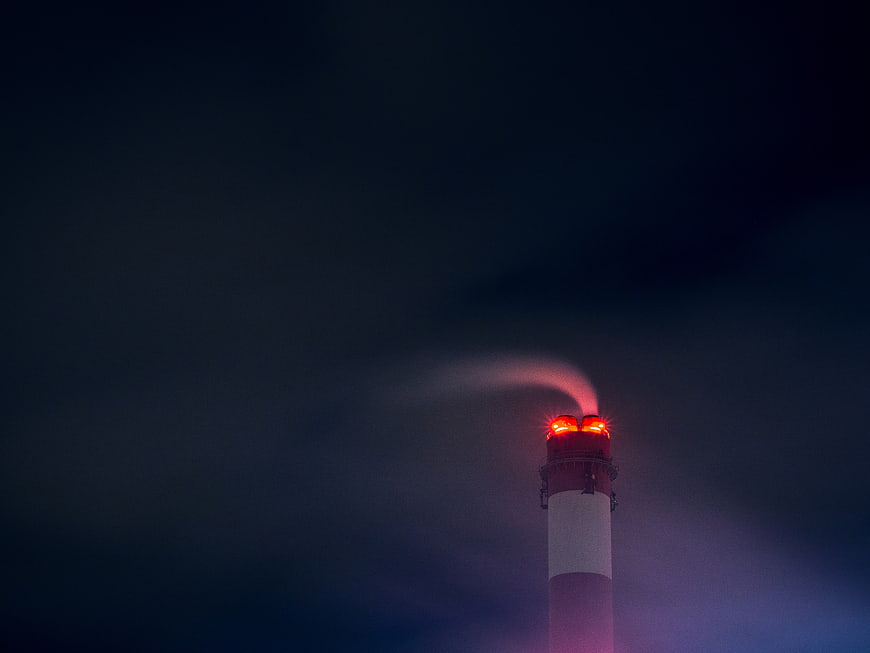Industrial Chimney with Red Warning Lights Emitting Smoke at Night