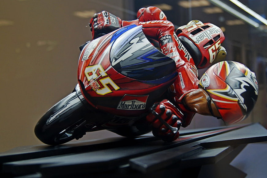 Red racing motorcycle model leaning into a turn