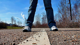 Low angle view of sneakers on asphalt road with white line