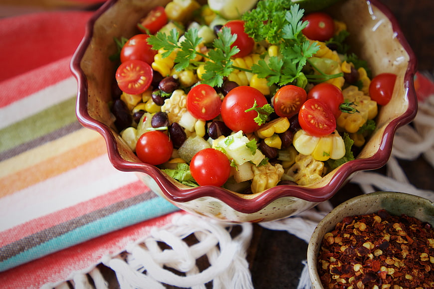Fresh corn and black bean salad with tomatoes in ceramic bowl