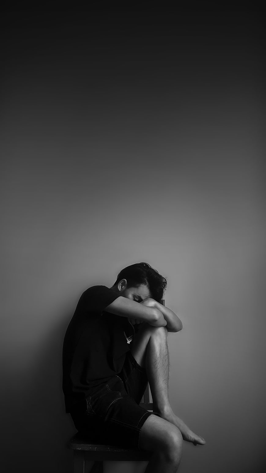 Sad Young Man Sitting Alone in Black and White Portrait