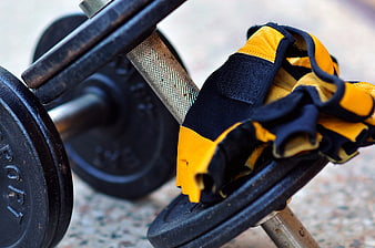 Close-up of yellow and black workout gloves on a dumbbell
