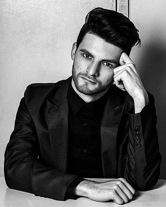 Handsome man in black suit posing in black and white portrait