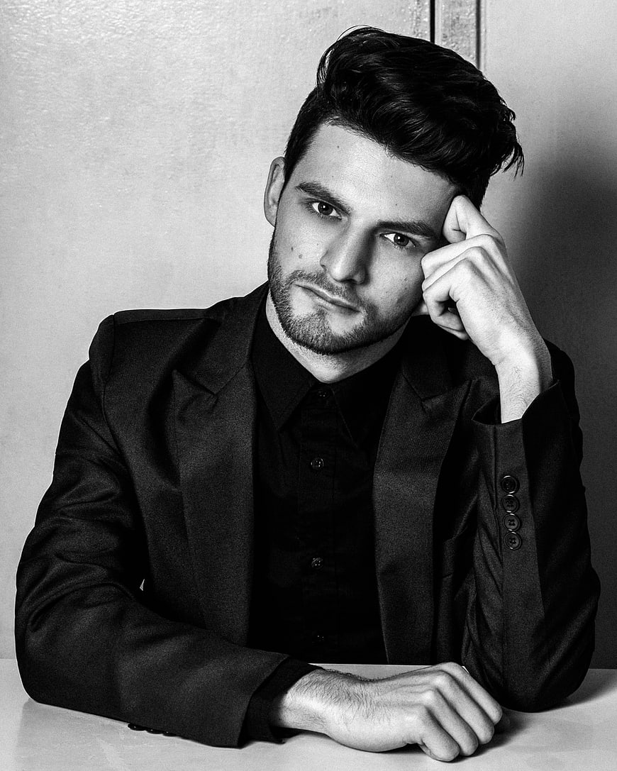 Handsome man in black suit posing in black and white portrait