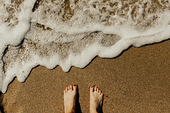 Top View of Bare Feet on Sandy Beach with Ocean Foam