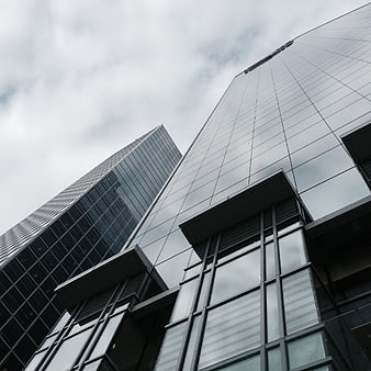 Low angle view of modern glass skyscrapers against cloudy sky