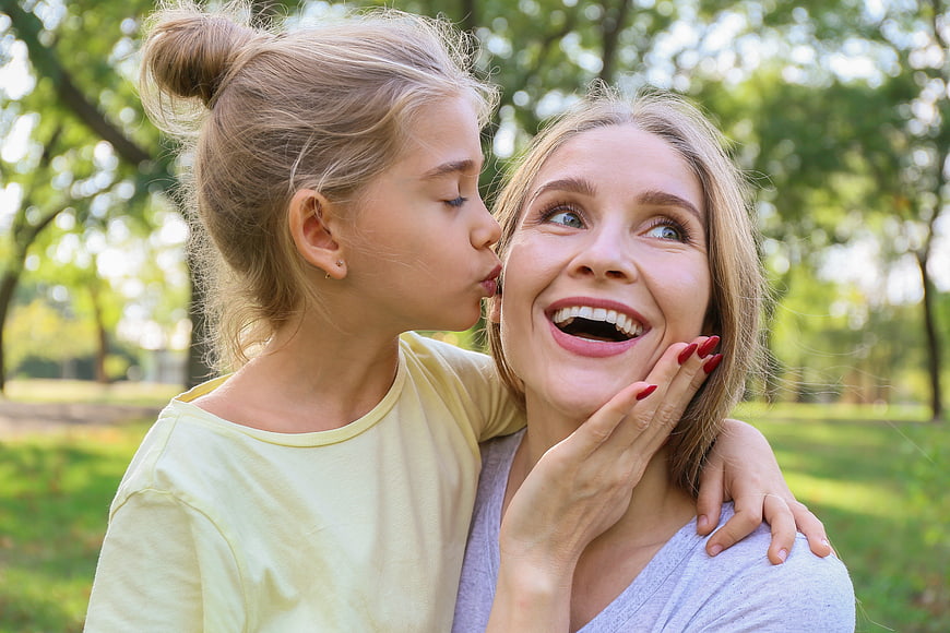 Happy mother and daughter laughing together in a park