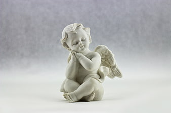 White porcelain praying angel figurine on gray background
