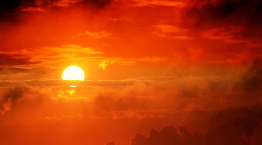 Vibrant Orange Sunset Sky with Sun and Clouds