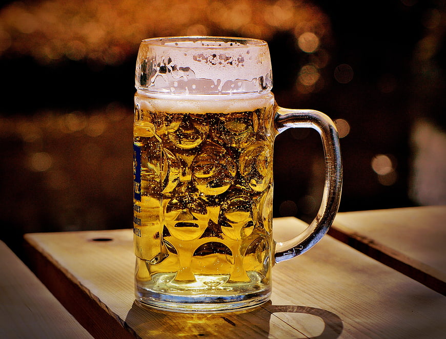 Cold beer mug with condensation on wooden table