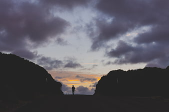 Silhouette of lone walker on road at sunset