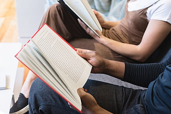Close-up of two people reading books together on a couch