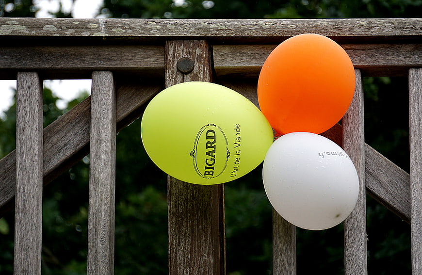 Colorful balloons tied to a wooden fence outdoors