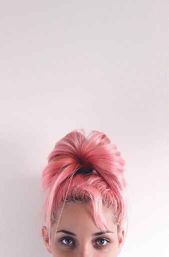 Close-up portrait of woman with pink hair bun and blue eyes