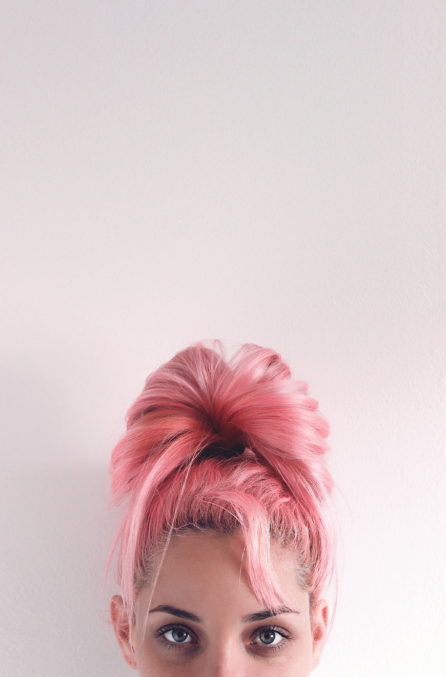 Close-up portrait of woman with pink hair bun and blue eyes