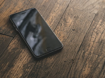 Black smartphone on rustic wooden table with empty screen