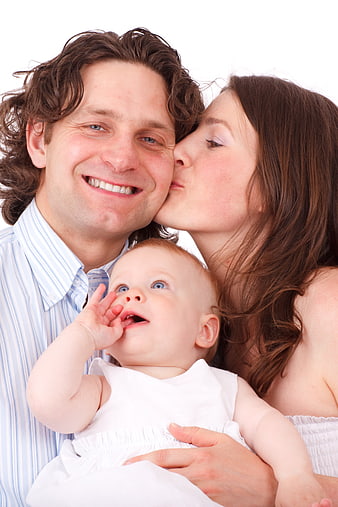 Happy family portrait with mother kissing father and baby