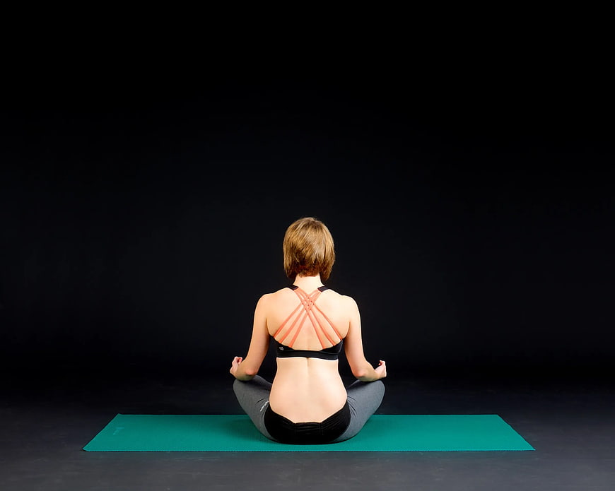 Woman Meditating on Yoga Mat from Behind