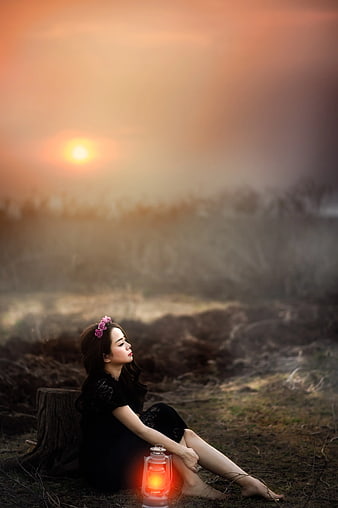 Woman Sitting with Lantern at Sunset