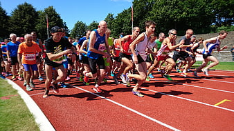 Group of athletes sprinting on a red running track