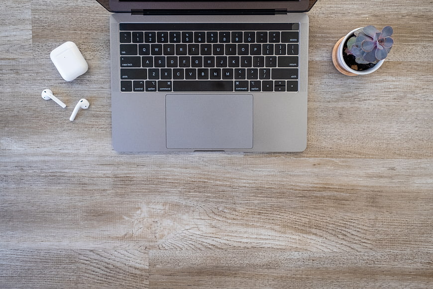Top View of Laptop Workspace with AirPods and Succulent