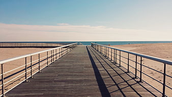 Wooden Boardwalk Leading to Ocean Beach on Sunny Day